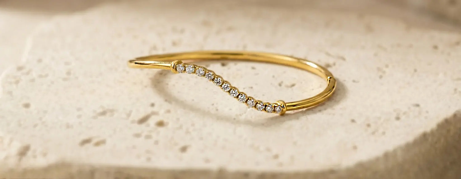 Gold bracelet with pave diamonds on a beige stone surface